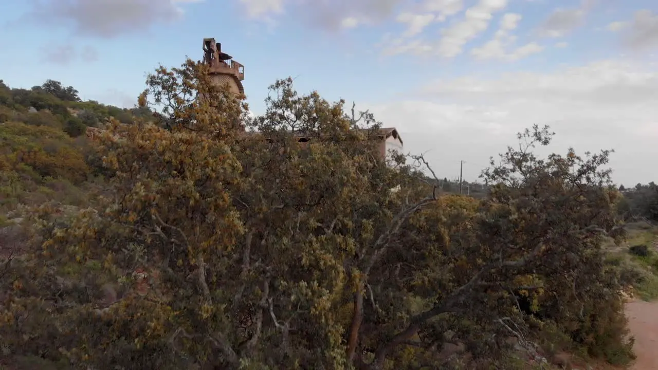 Old derelict quicklime factory with graffiti drone rising reveal from behind tree