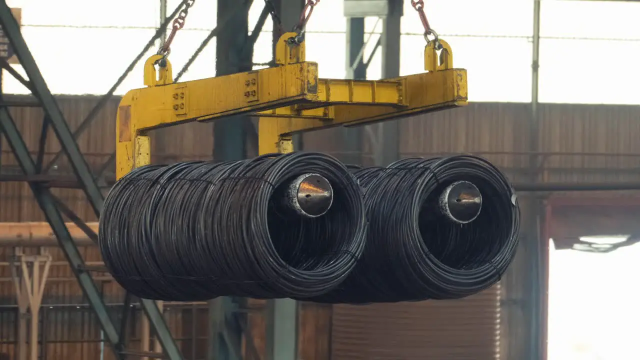 Overhead crane carrying steel cable inside factory