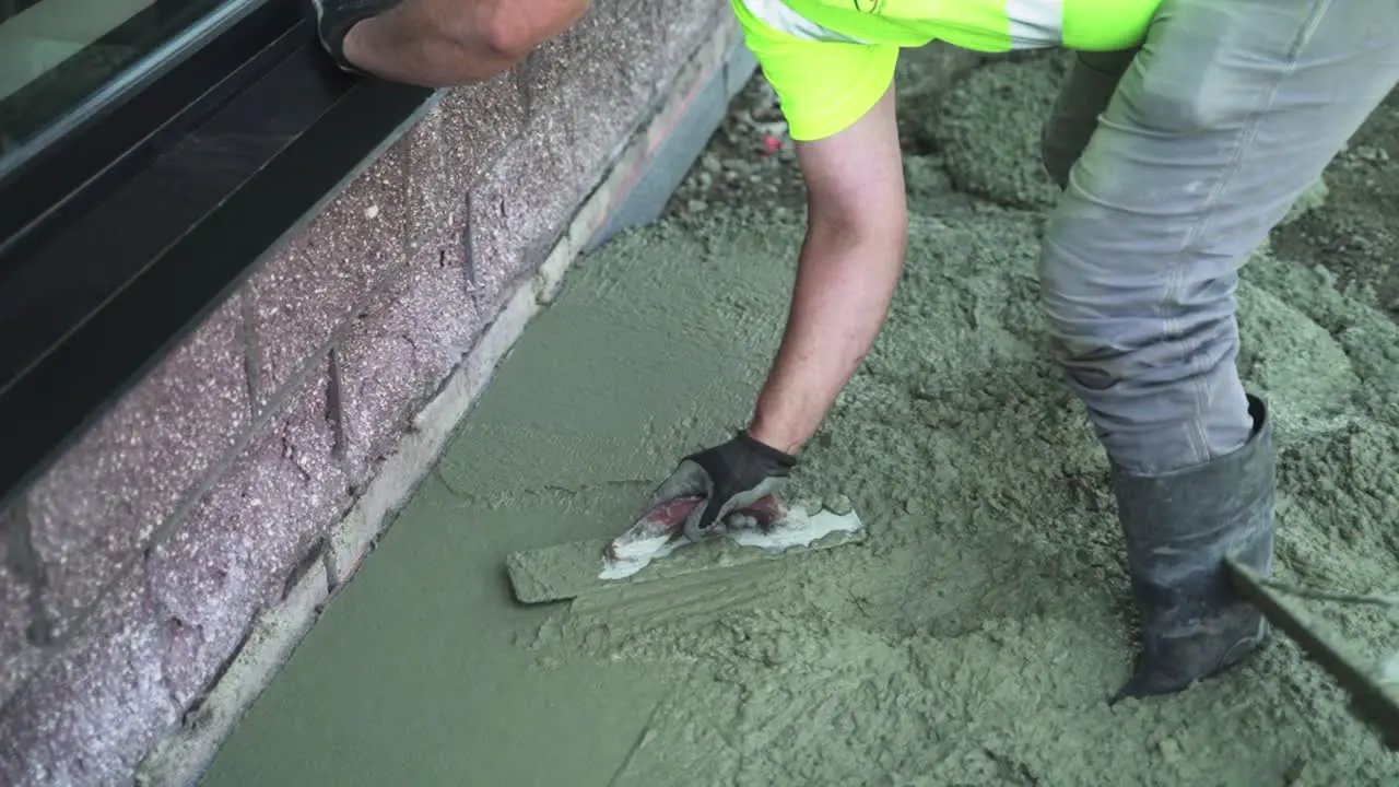 Construction worker spreading concrete cement flooring with trowel