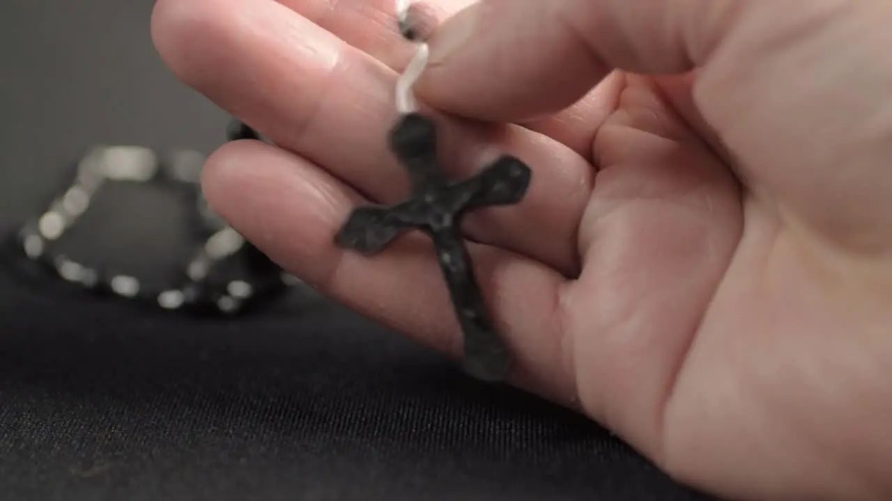 Hand holding string of rosary beads with crucifix close up