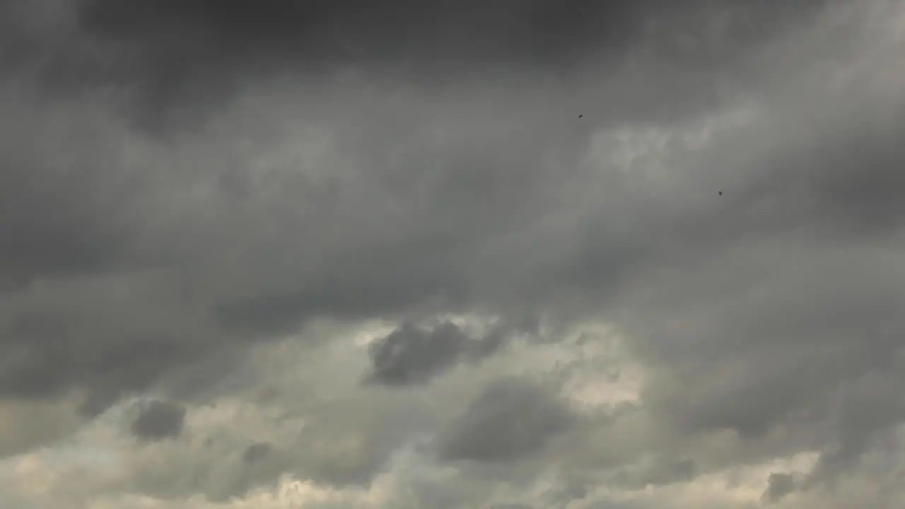 Dark threatening thick time lapse of clouds passing by in diminishing blanket of clustering water droplets in the air making a dramatic cinematic scenery clearing up revealing blue sky at sunset