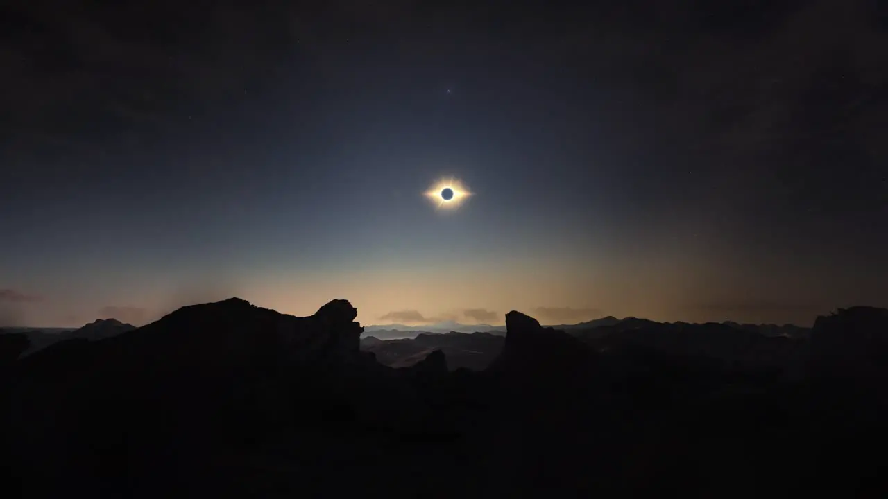 Timelapse movement of clouds above solar eclipse on rocky landscape at dusk