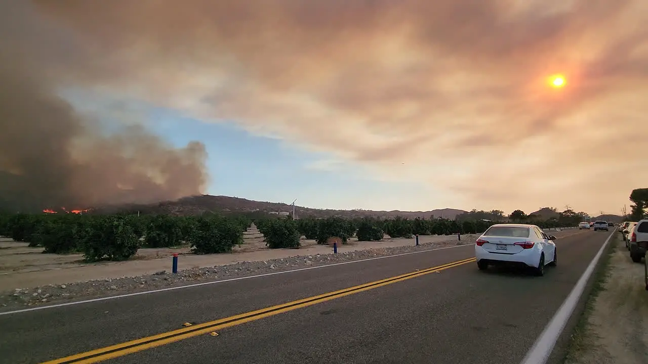 Car traffic next to the Fairview Fire burning hill and thick black smoke in Hemet California