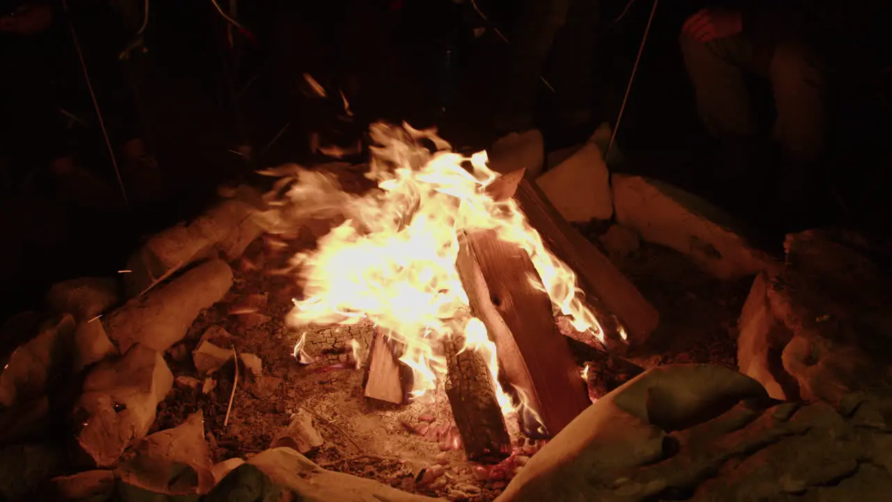 Campers sitting around large campfire in stone ring