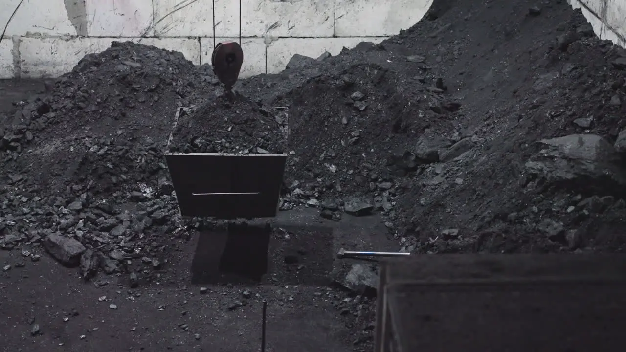 Lifting coal bucket with hoist from pit at heating station