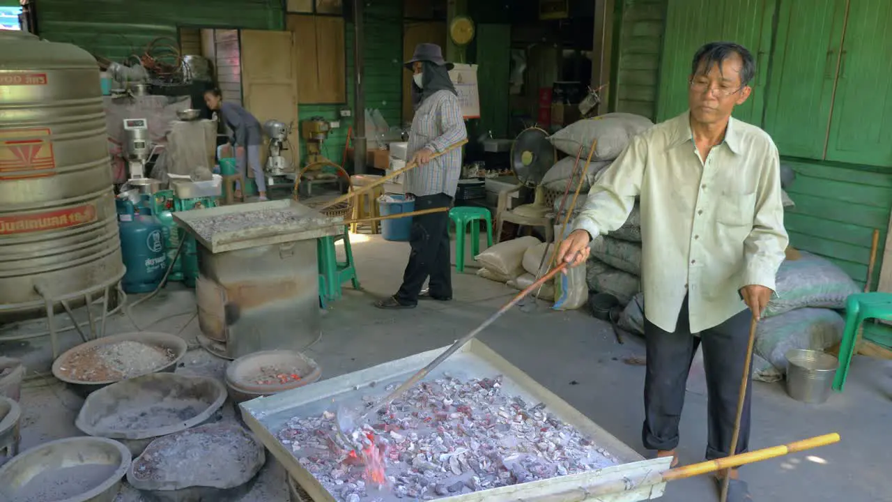 Thai cookie factory workers using coal and metal containers for baking slow motion