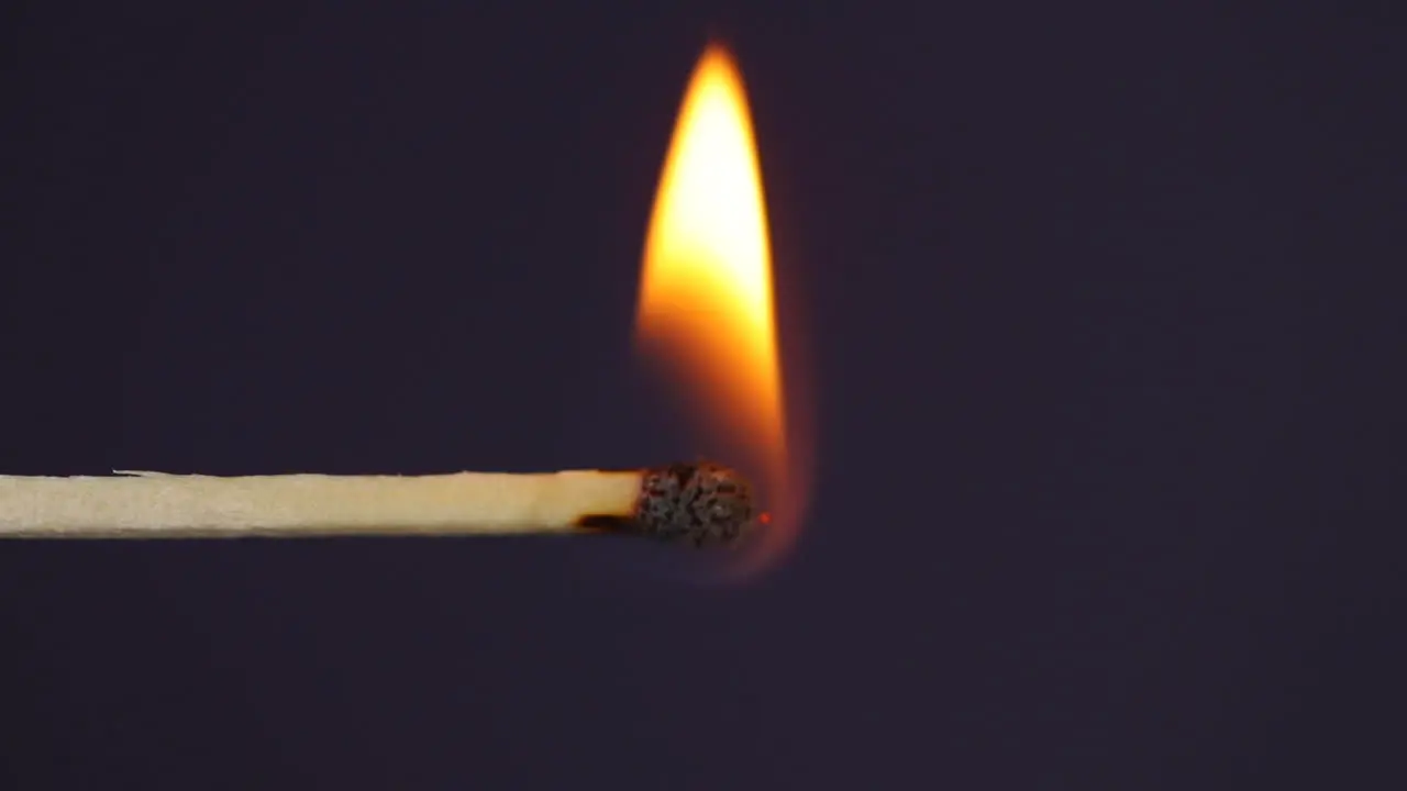 Hand igniting matches close up macro shot captured from left side of black background in slow motion at 60 fps