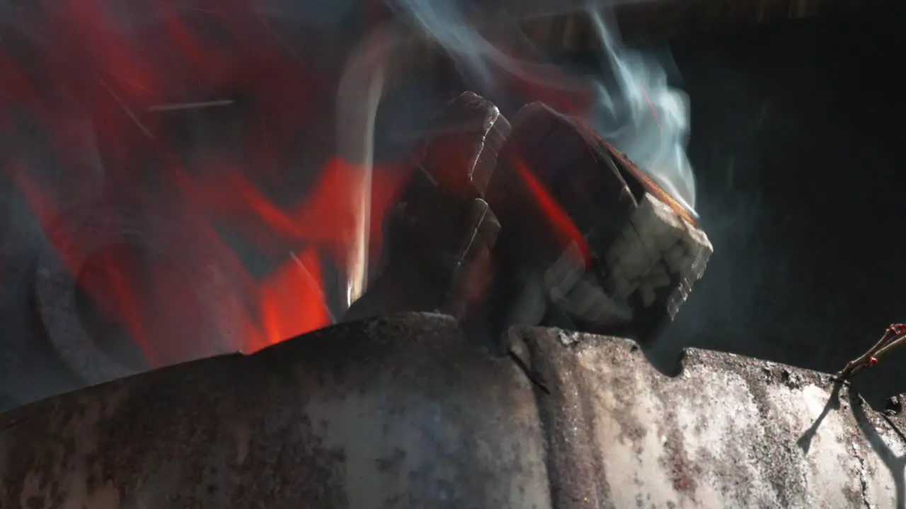 Adjusting burning logs with metal tool