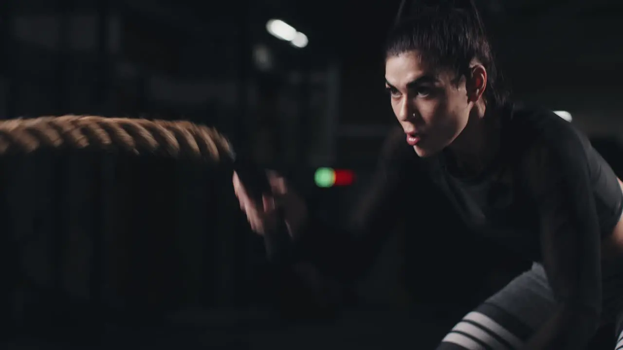 Young woman training with battle ropes in the gym