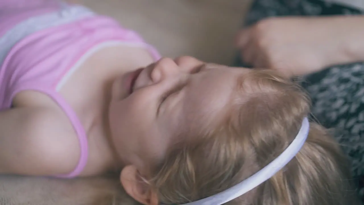 careful mother drops little girl eyes on soft bed in room