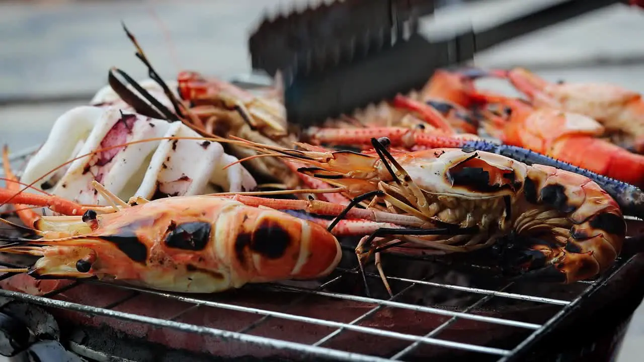 a side view of grilled shrimps that are being turned by a thai girl Thailand