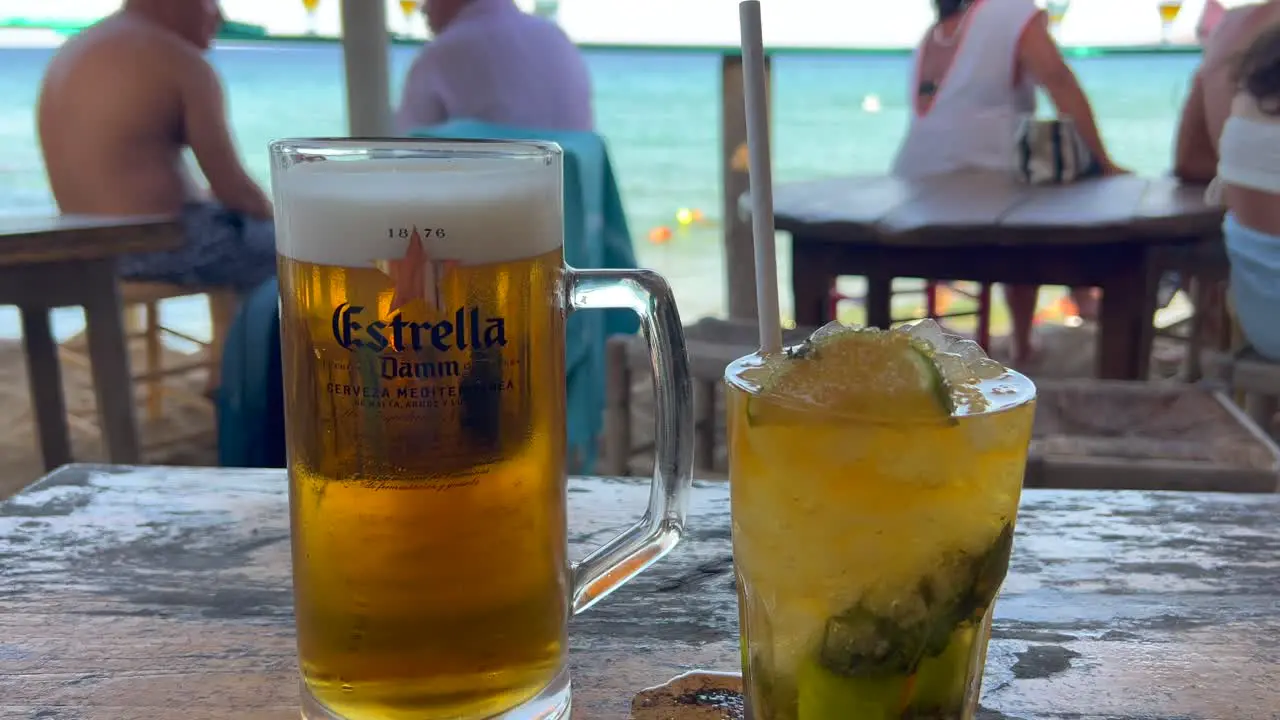 Nice cold beer and mojito cocktail at a beautiful beach bar refreshing drinks enjoying summer with dreamy holiday sea view in Ibiza Spain vacation destination 4K shot