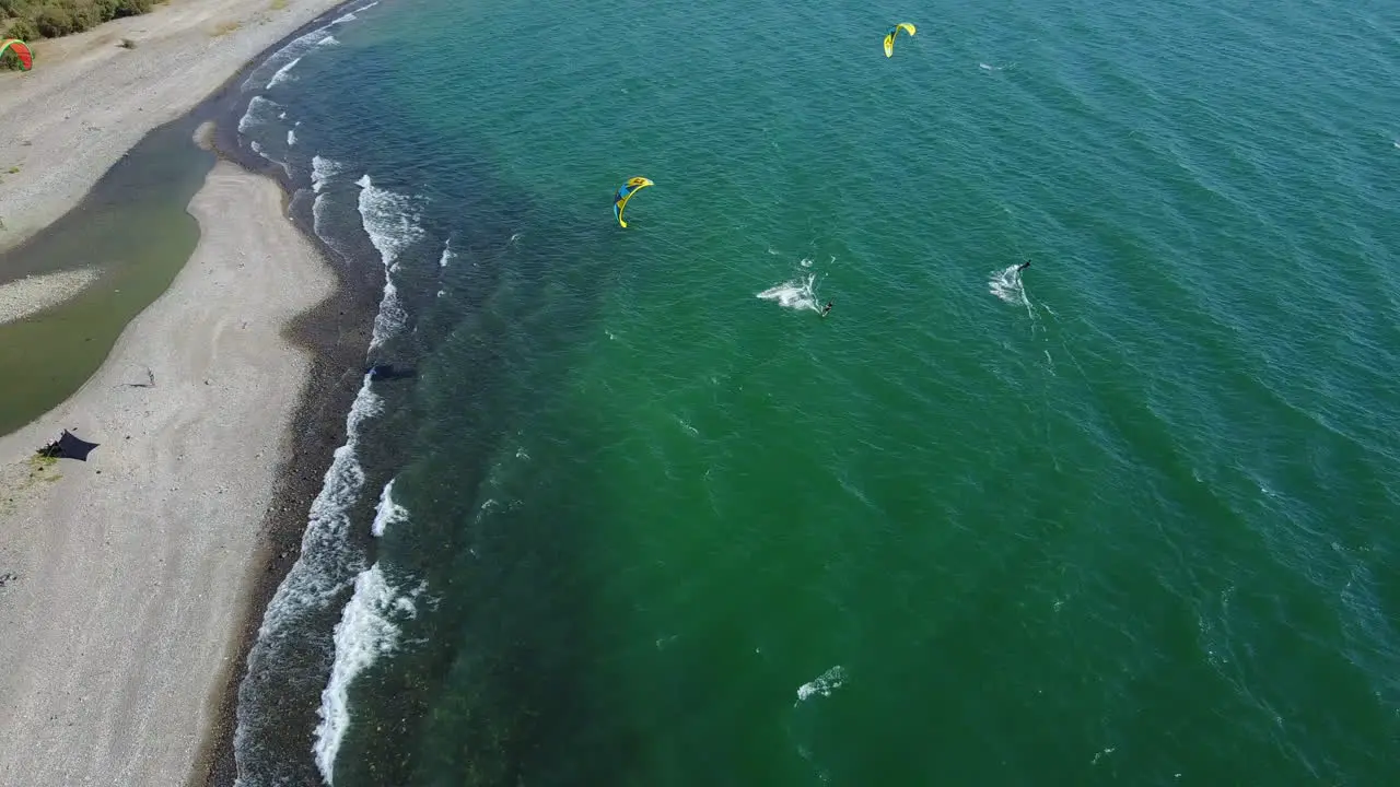 Drone footage of Kitesurfers surfing along the beach of the Sea of Galilee in Israel