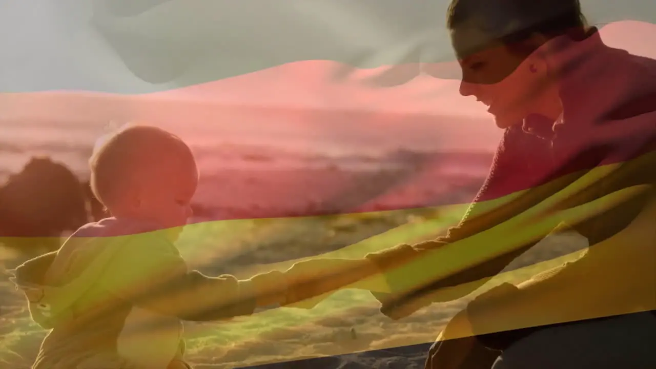 Animation of german flag over caucasian mother and child playing on beach