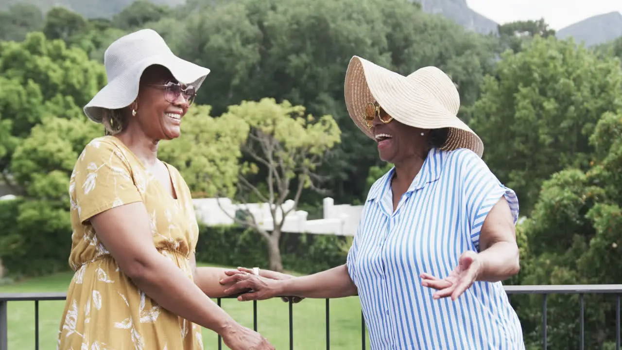 Portrait of happy senior african american female friends outside in sunglasses and hats slow motion