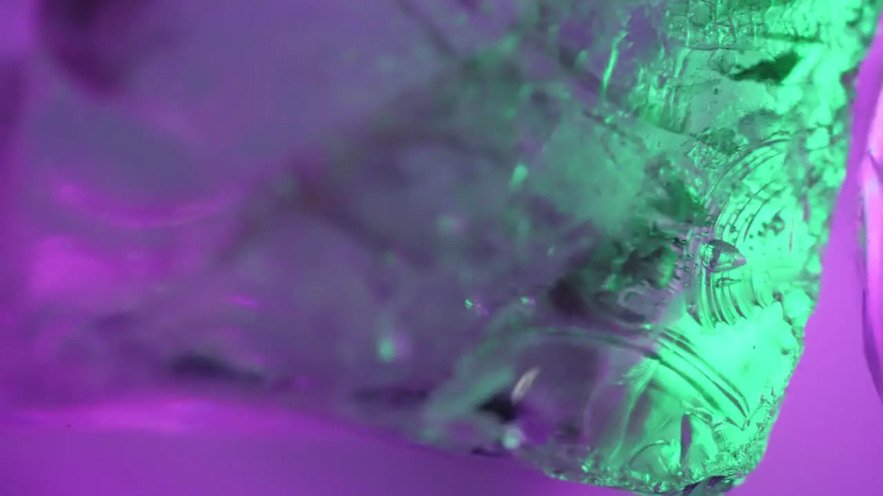 Macro abstract background transition or overlay layer as purple and green lights pass through a rotating crystal