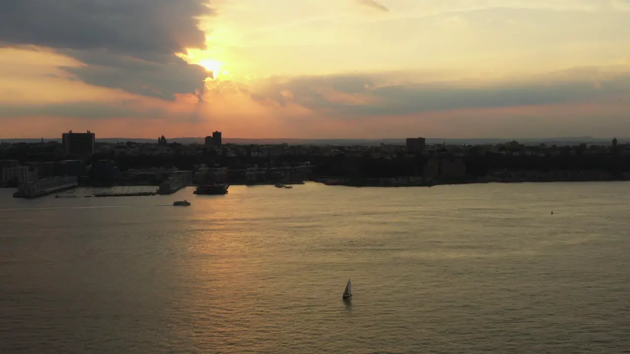 drone ascends truck right up to golden sunset with ferry sailboat on the Hudson River with New Jersey in the background