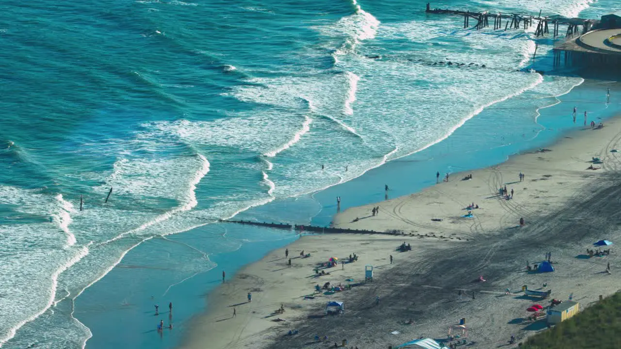 An aerial shot of deep blue and white cresting waves crashing on the sandy brown beach of Atlantic City NJ