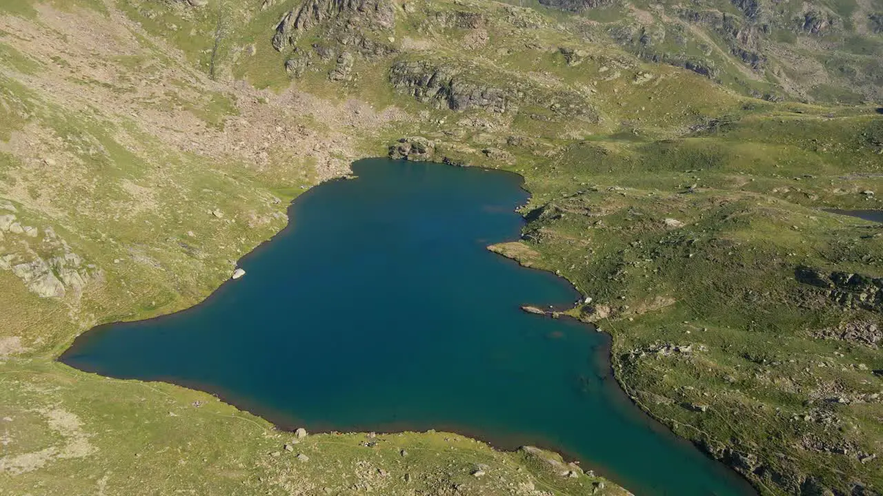 Drone footage of a turquoise lake in the Pyrenees mountains