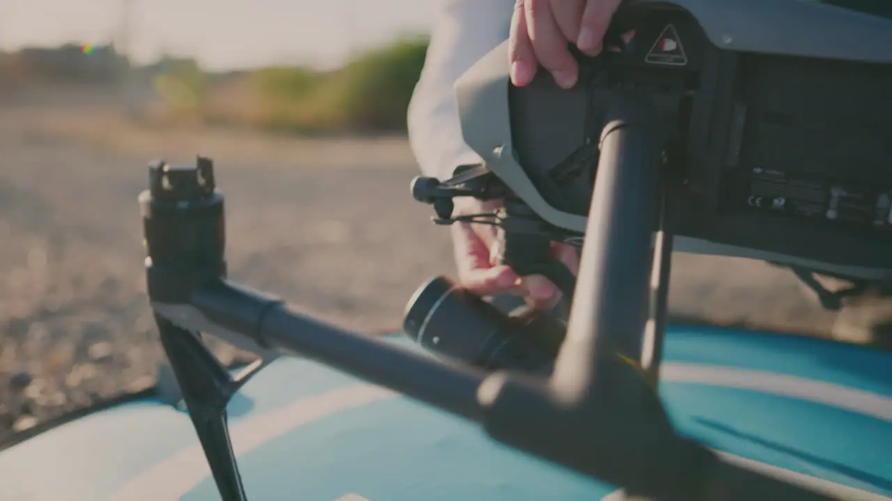 A person putting a camera on a drone with plants and the sky in the background