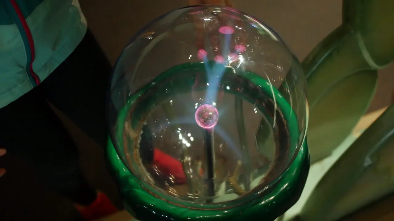 A girl puts fingers onto a plasma ball emitting electrical charge