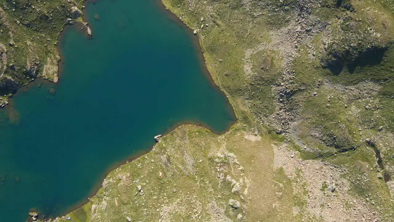 Top-down drone footage of a turquoise lake in the Pyrenees mountains