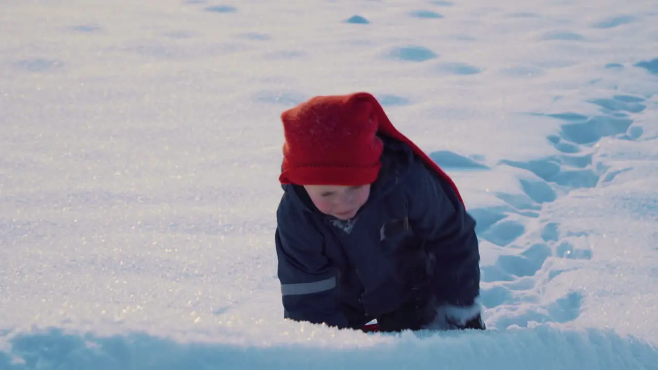 Determined young boy pulling his sled up the hill in the snowy landscape in Norway during Christmas