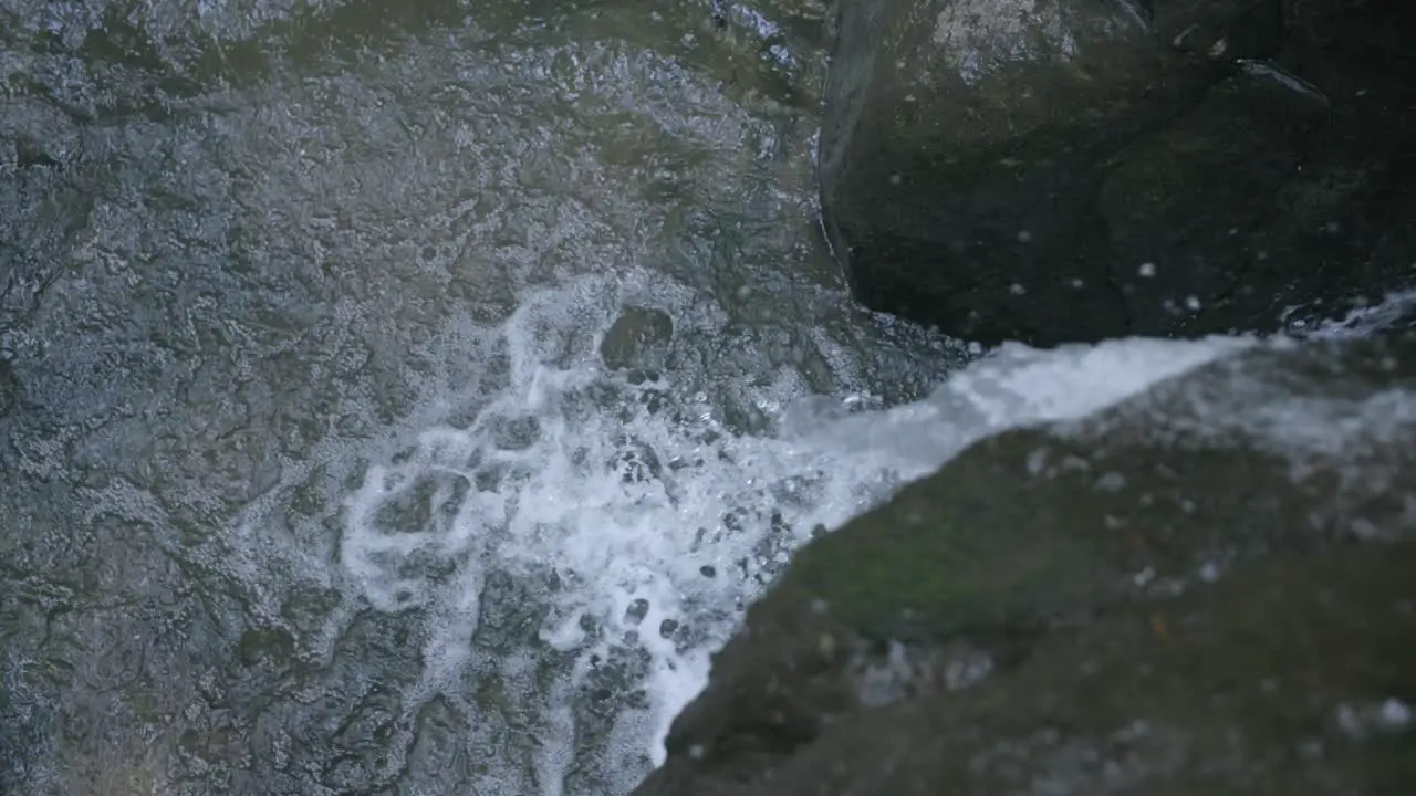 Slow motion footage of water crashing off a rock and falling into a pool of water