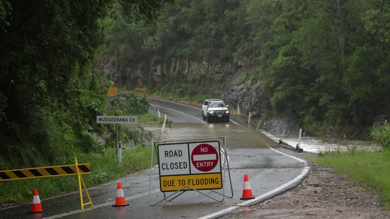 Mudgeeraba Gold Coast 02 January 2024 White 4wd crossing Mudgeeraba Creek Bridge on the Gold Coast Hinterland during flooding