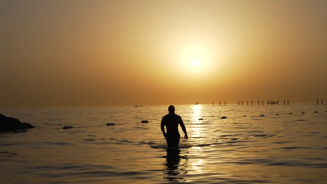 Man walking out of sea in Dubai Persian gulf Sunset