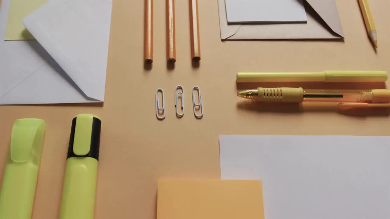 Close up of pens pencils and stationery arranged on beige background in slow motion