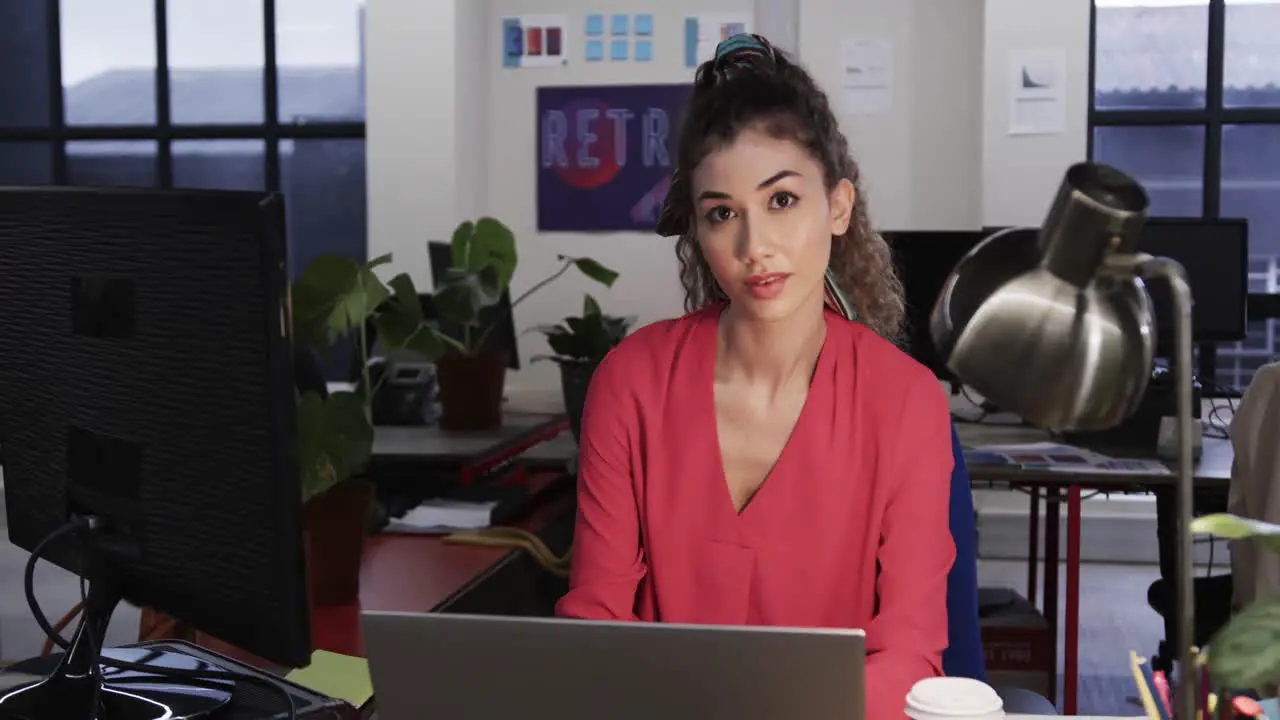 Happy biracial female creative using computer at casual office in slow motion