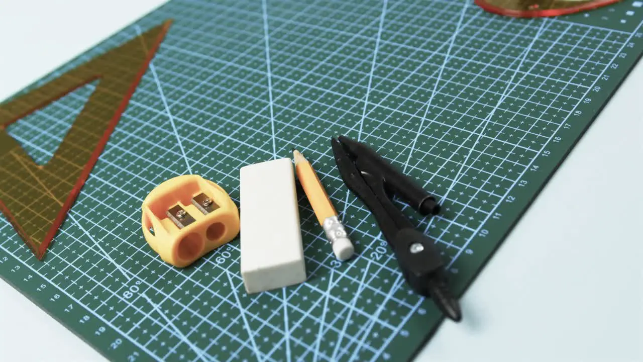 Compass pencil sharpener eraser and rulers with pad on white background in slow motion