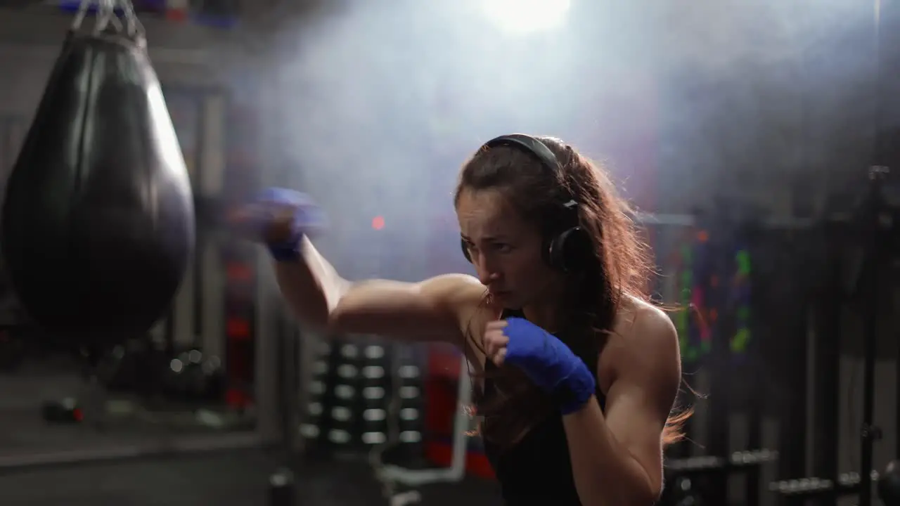 Concentrated Boxer Performing Active Punching In Bandages Wearing Headphones