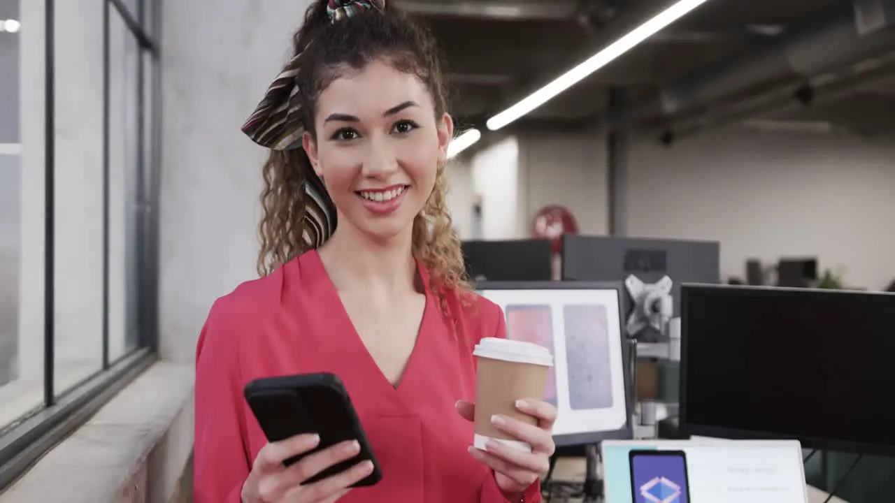 Happy biracial female creative using smartphone at casual office in slow motion