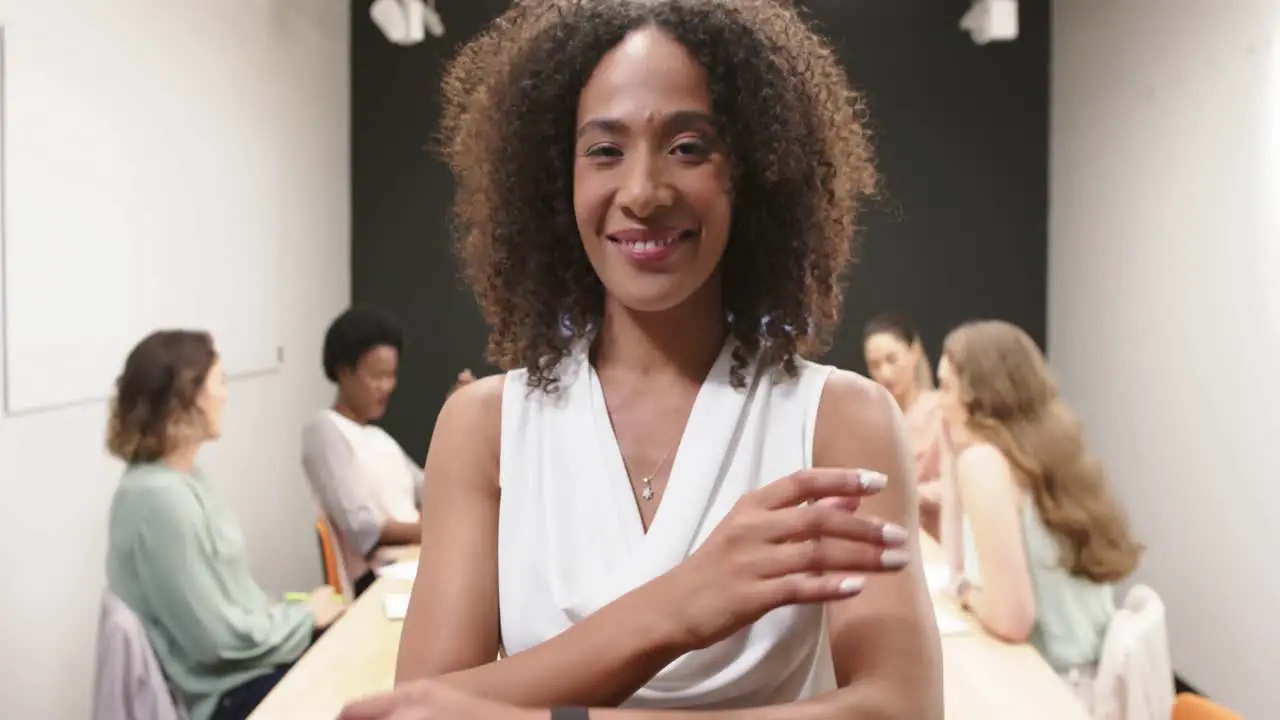 Portrait of biracial businesswoman with her diverse colleagues at meeting at office in slow motion