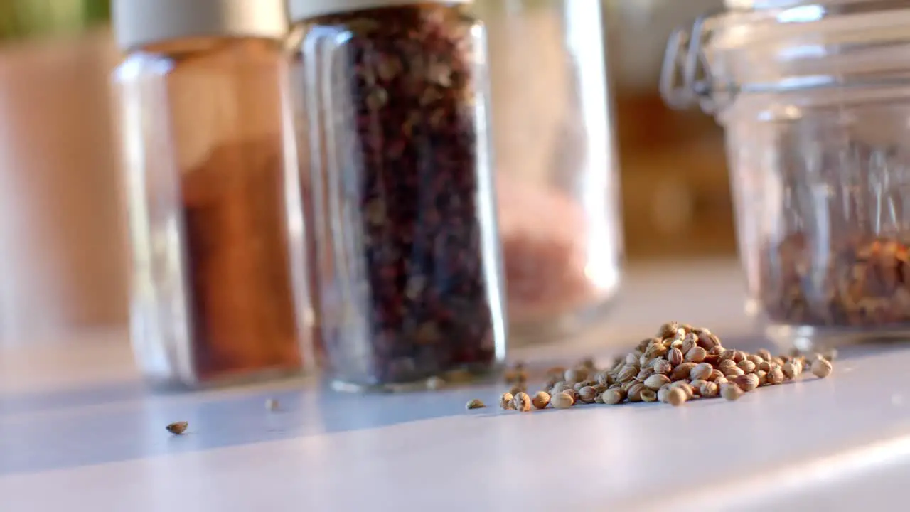 Storage jars of seasonings on countertop in sunny kitchen slow motion