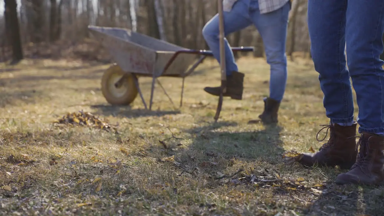 Close-up view of a woman is removing weeds in the countryside On the background her partner are looking her