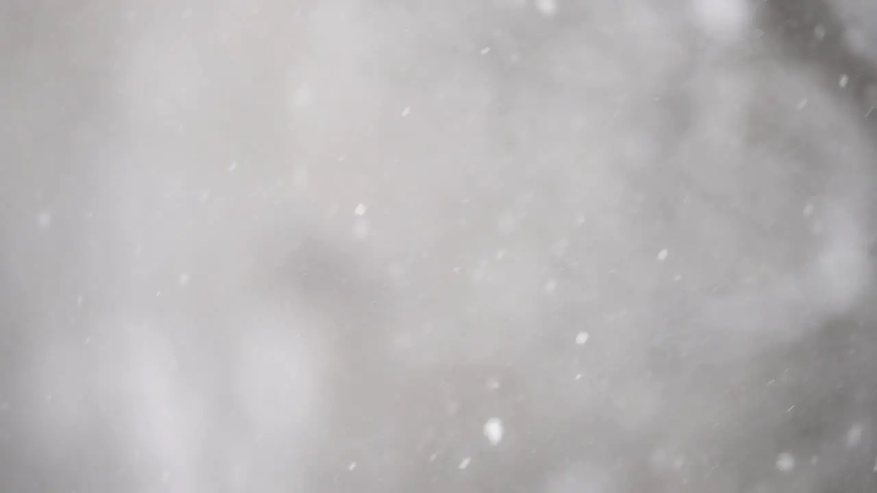 Snow falling in slow motion against a dark grey background