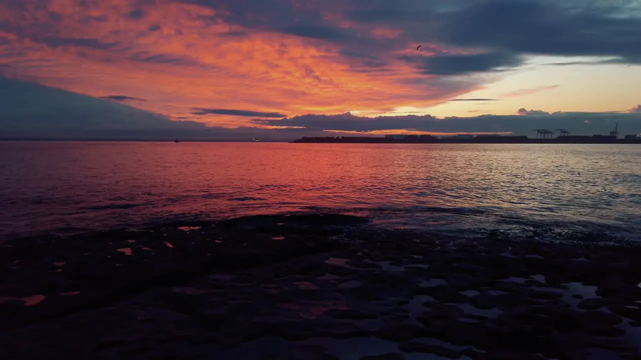 Tranquil sunset with red and orange clouds reflecting on surface of ocean slow