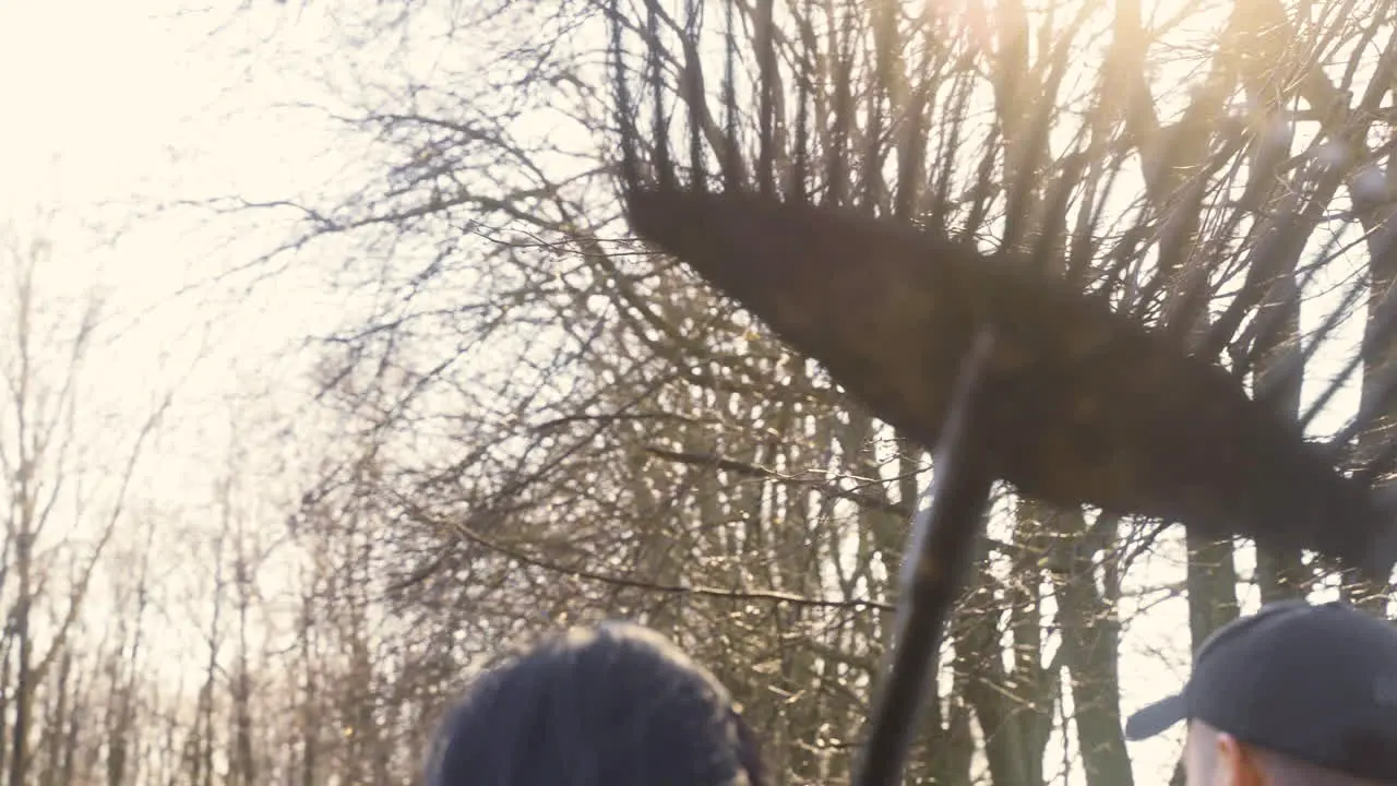 Rear view of a caucasian woman holding a rake while walking with her partner throught the countryside