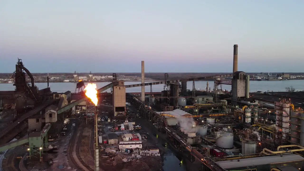 Zug Island Steel Factory Steel mill in Detroit Michigan aerial panning shot with burning chimney at twilight