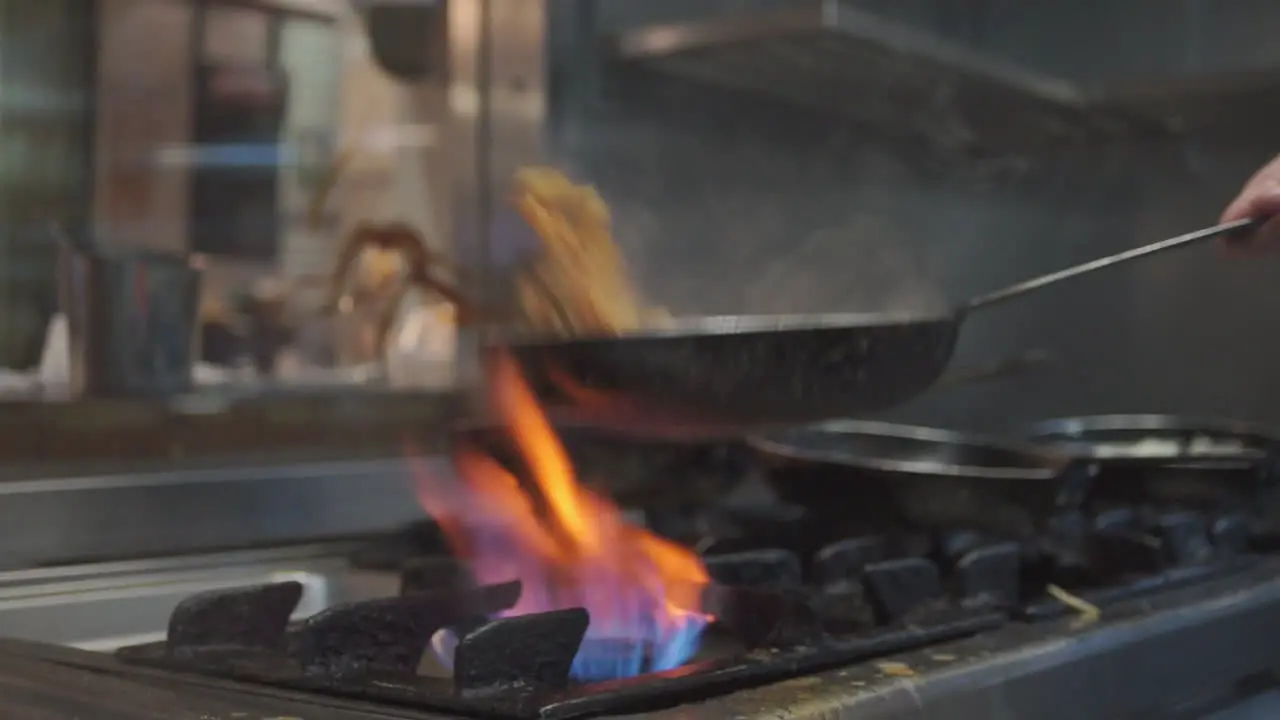 Shot Inside A Kitchen Of An Italian Restaurant Where A cook Prepares Pasta In A Pan