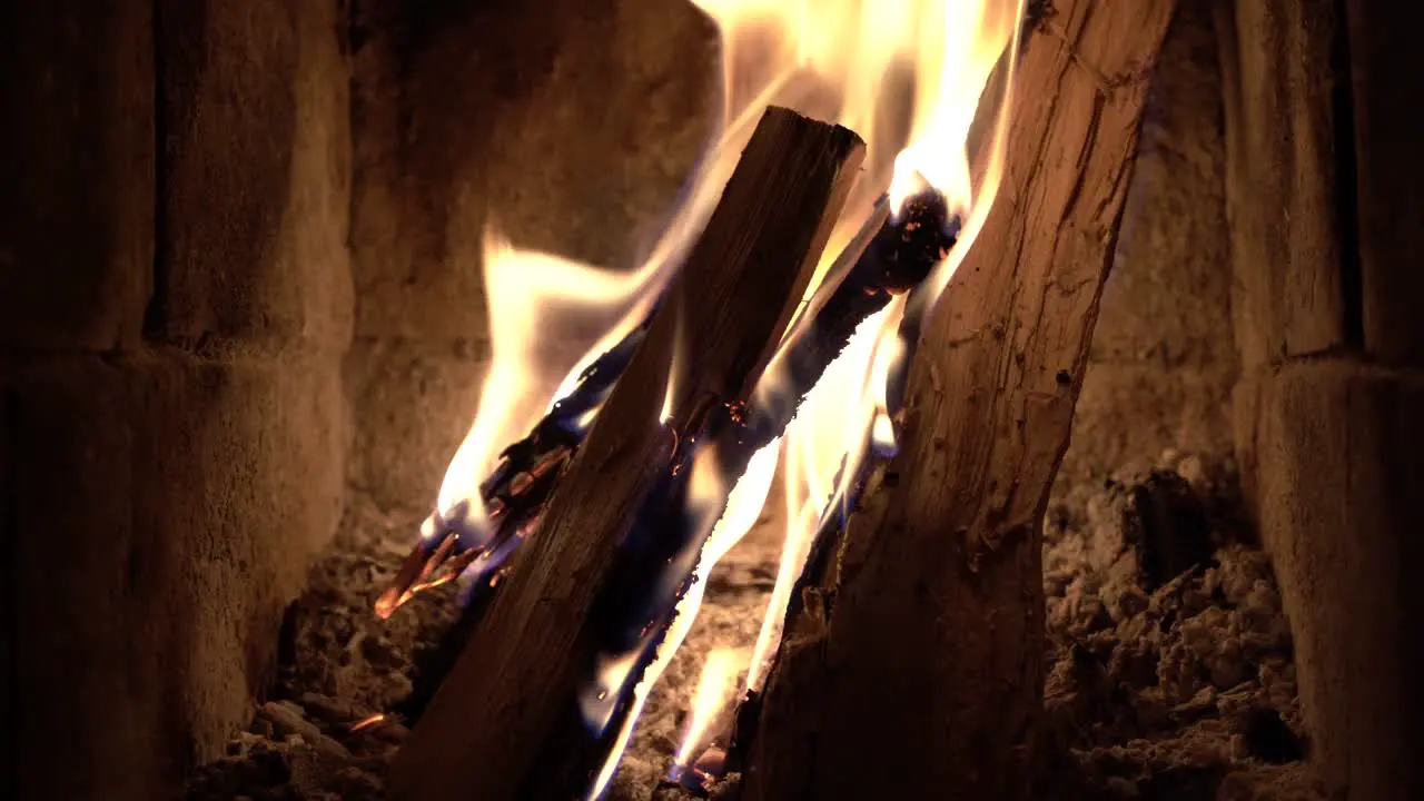 Medium shot of wooden logs burning in an indoor fireplace