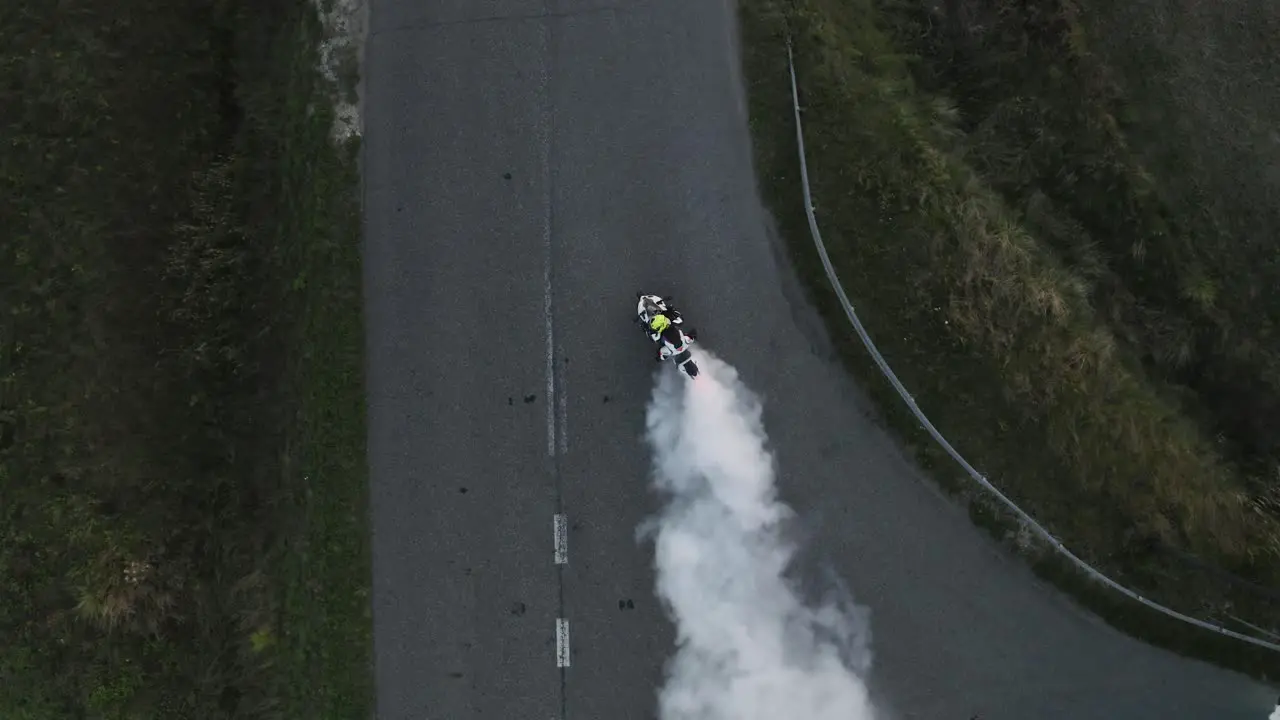 Aerial top down view of motorcycle burning tire with lots of smoke