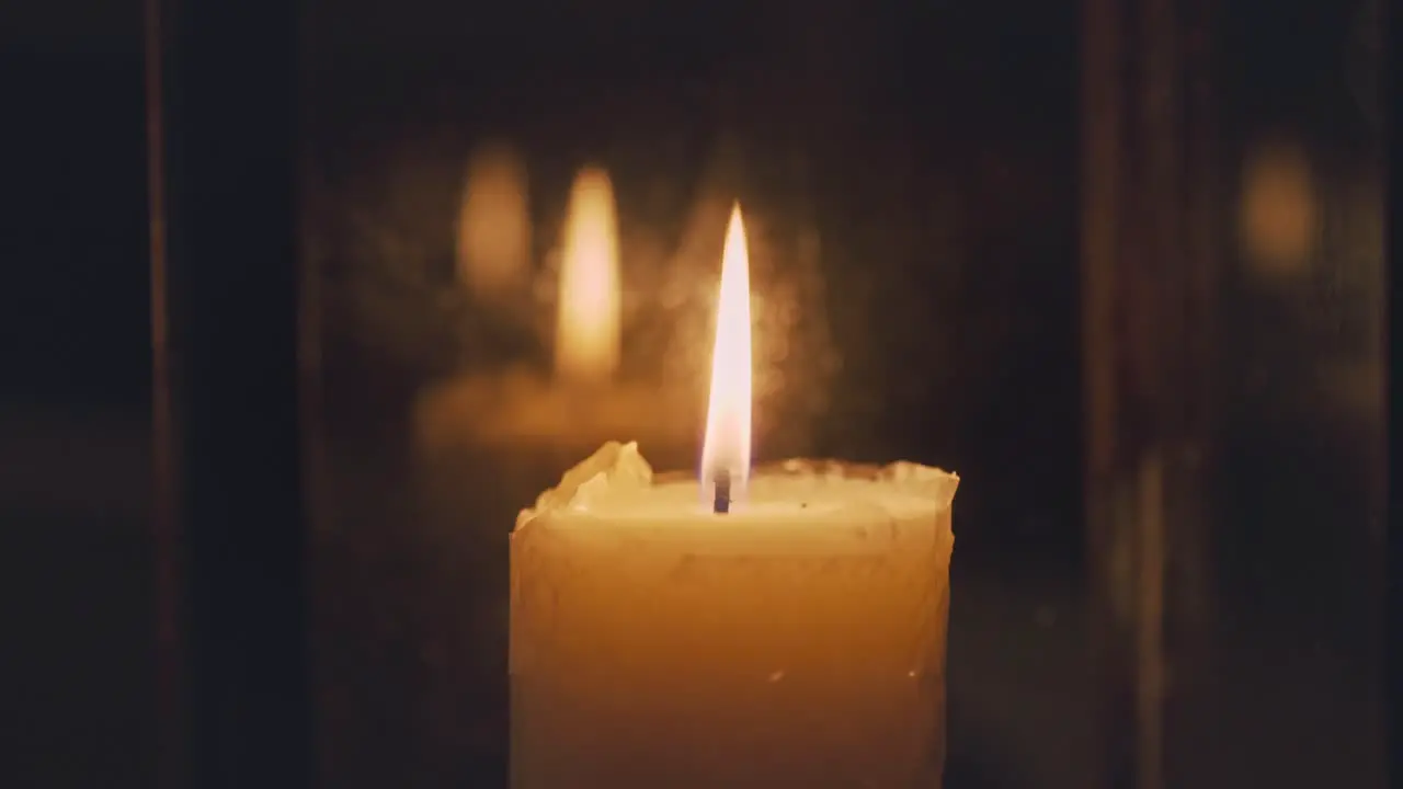 Close up of candle flame burning inside glass latern at night