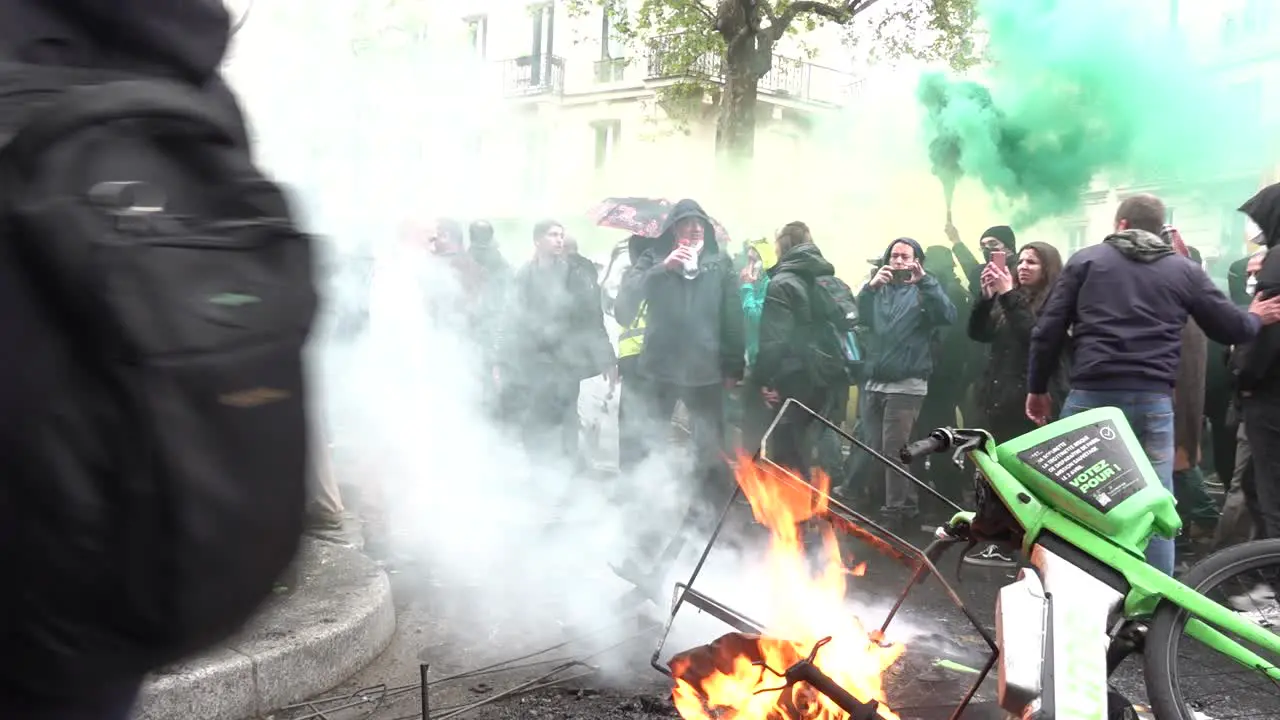 Rioter holds sign in front of burning bike in Paris France