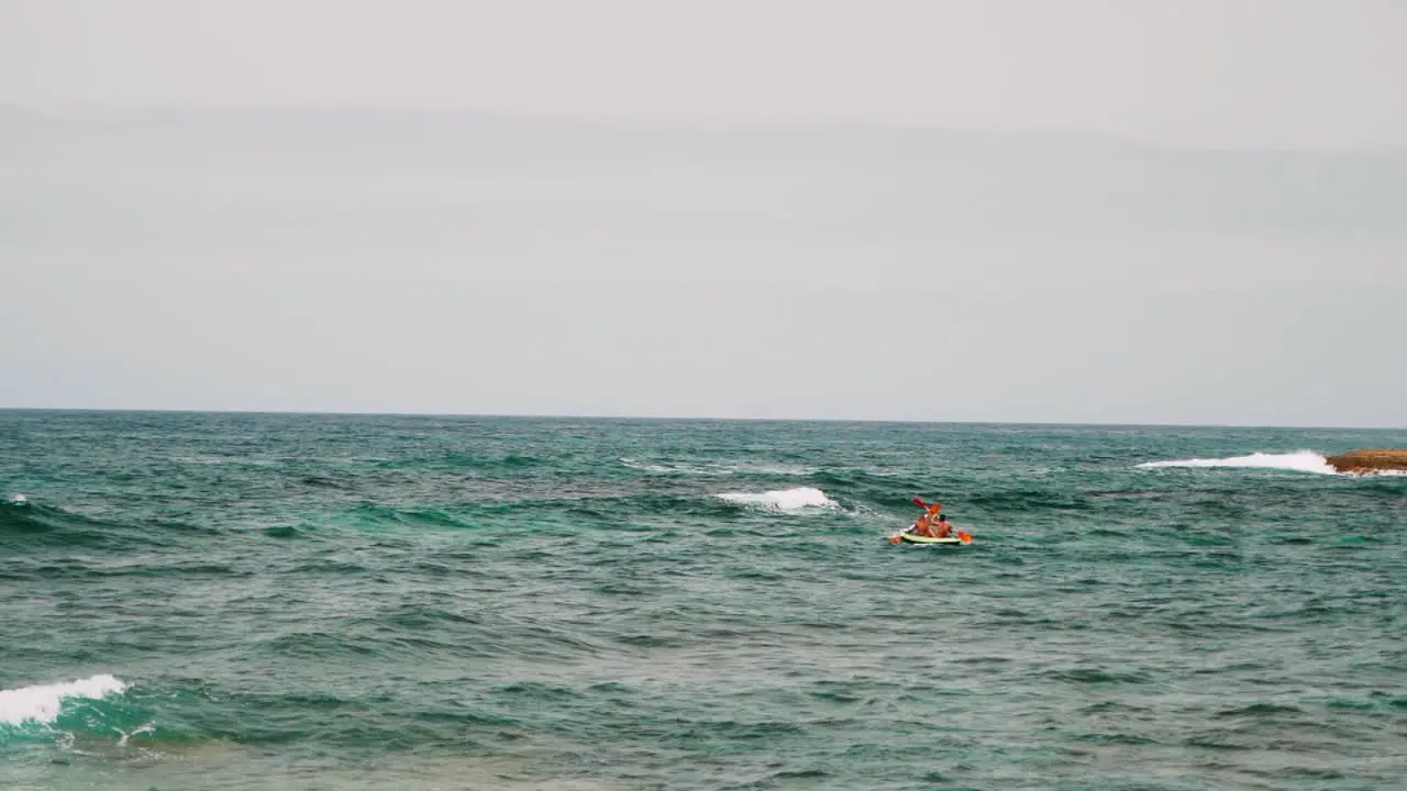 Slowmo wide shot of people rowing Paddle On A paddle Boat during waves on the ocean