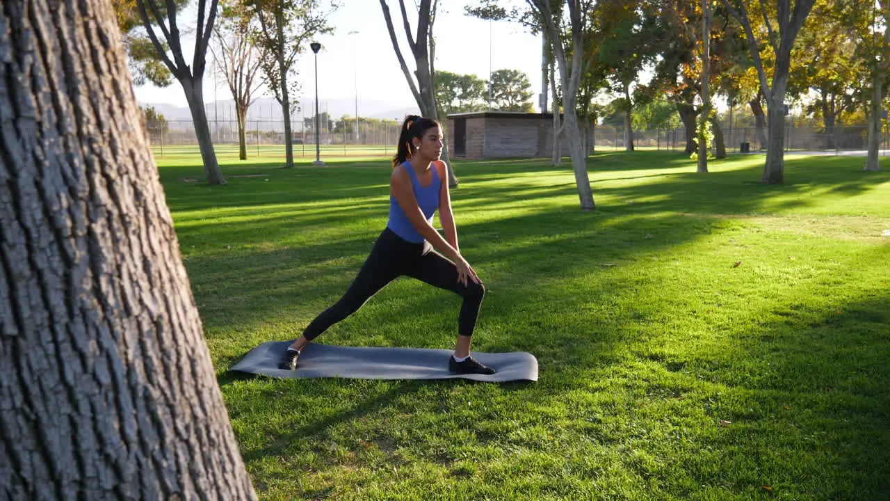 A healthy young woman stretching her legs before a fitness workout in the park at sunset SLOW MOTION