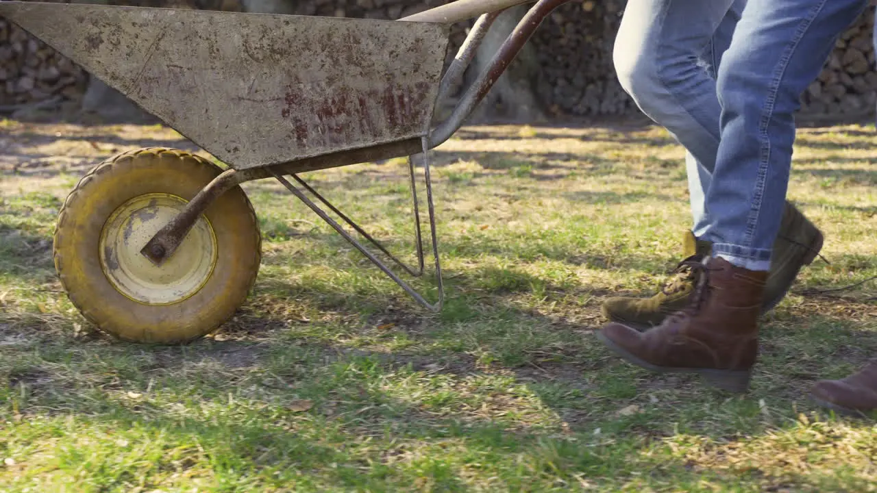 Close-up view of caucasian couple feet walking throught the countryside while they are carrying a wheelbarrow